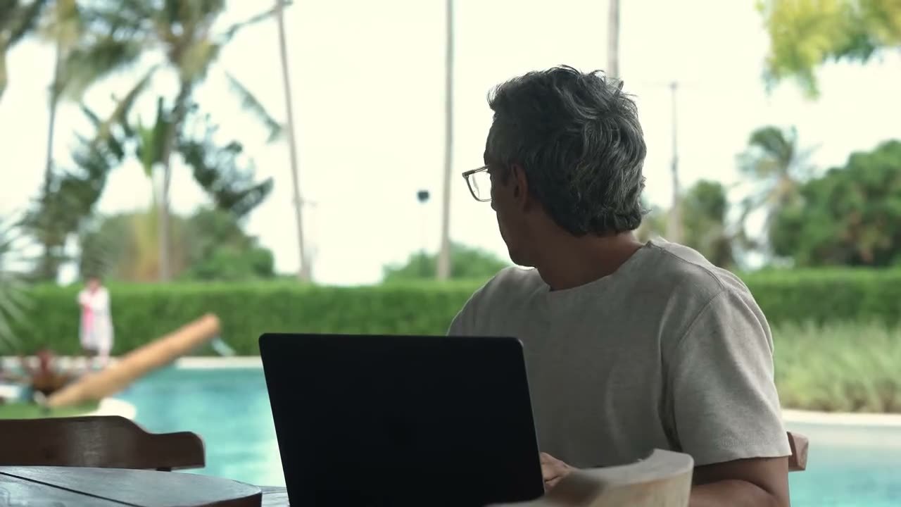 Quadro do filme da Rapport: um dono de empresa trabalha no notebook na beira da piscina